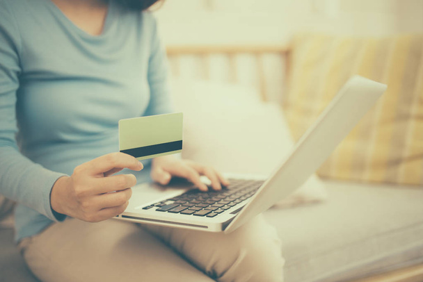 Concepto de compras online. Joven mujer asiática sosteniendo tarjeta de crédito y el uso de ordenador portátil
.  - Foto, imagen