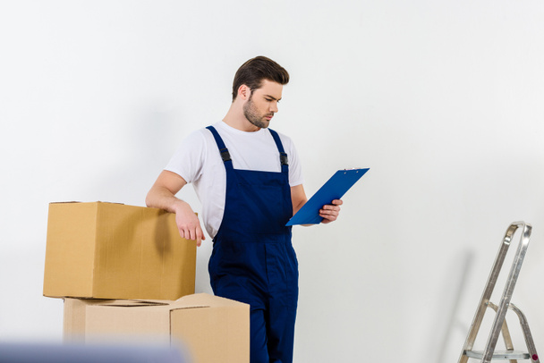 thoughtful relocation service worker looking at clipboard  - Photo, Image