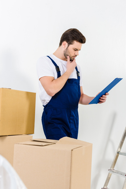 thoughtful relocation service worker looking at clipboard  - Photo, Image