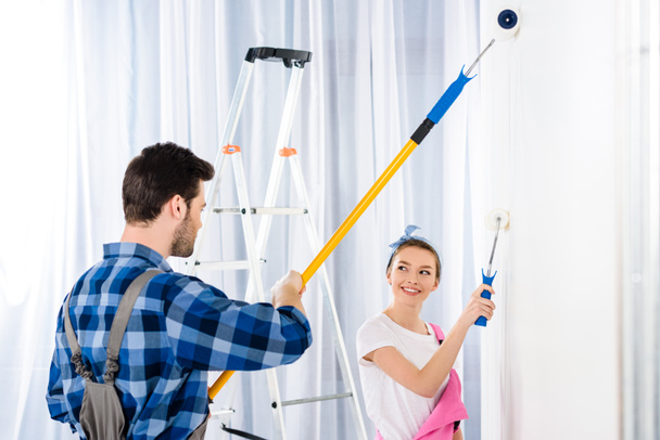 boyfriend and girlfriend painting wall with white paint - Foto, immagini