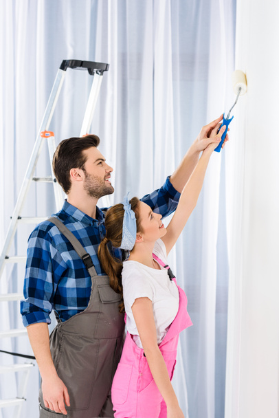 boyfriend helping girlfriend painting wall - Photo, Image
