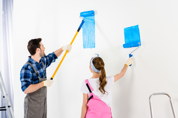 boyfriend and girlfriend painting wall with blue paint - Фото, изображение