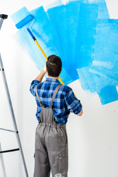 adam boyama duvar mavi boya ile dikiz - Fotoğraf, Görsel