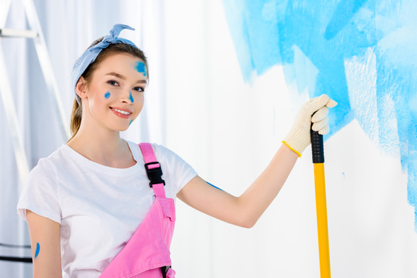 smiling girl holding paint roller brush and looking at camera - Photo, Image