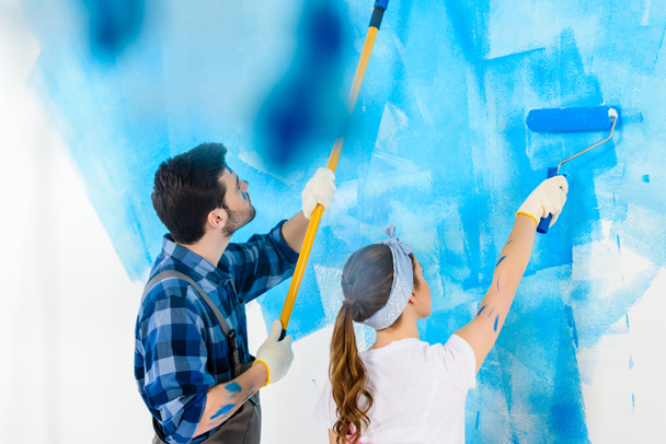 boyfriend and girlfriend painting wall with blue paint - Φωτογραφία, εικόνα