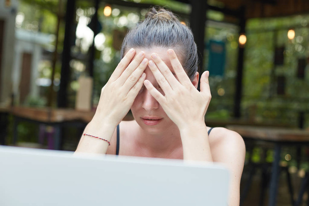 Elégedetlen fiatal barna női szabadúszó munkavállaló boldogtalanul, amely az arcát kezével, hogy hiba, miközben ül a számítógép képernyőjén fából készült asztal kemény munkanap folyamán portréja. - Fotó, kép