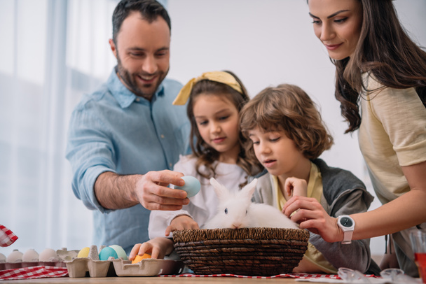 young family preparing for easter holiday with rabbit sitting on table - Photo, Image