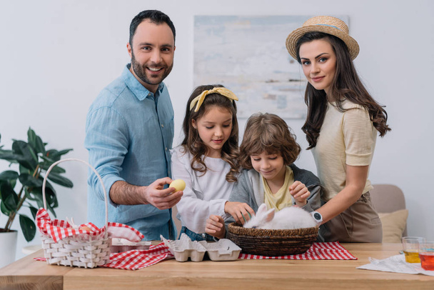 Junge Familie mit bunten Eiern und Hasen bereitet sich auf Ostern vor - Foto, Bild
