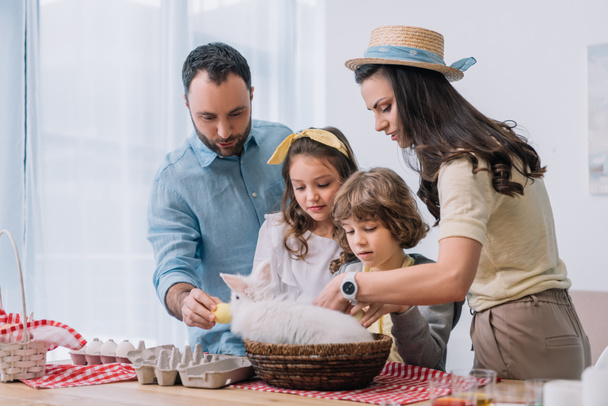 Nuori perhe leikkii pupun kanssa valmistellessaan pääsiäistä
 - Valokuva, kuva