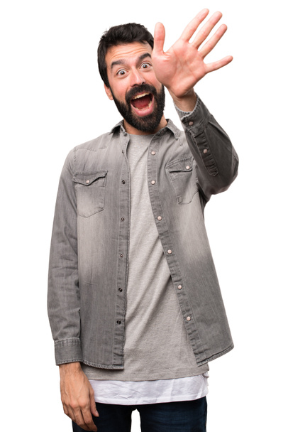 Hombre guapo con barba saludando sobre fondo blanco
 - Foto, imagen