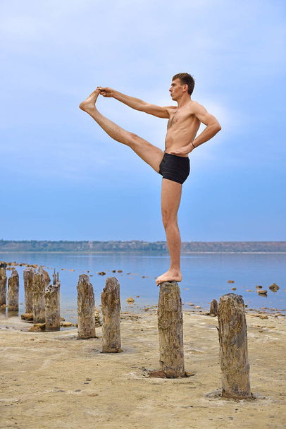 Man Athlete Makes A Stand On Wooden Pillars. - Foto, imagen