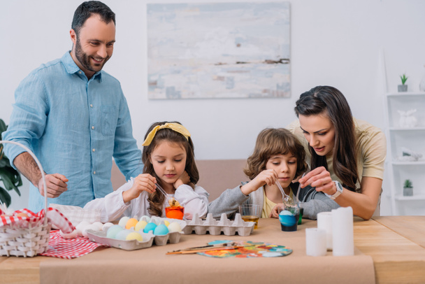 красива молода сім'я малює яйця на Великдень вдома
 - Фото, зображення