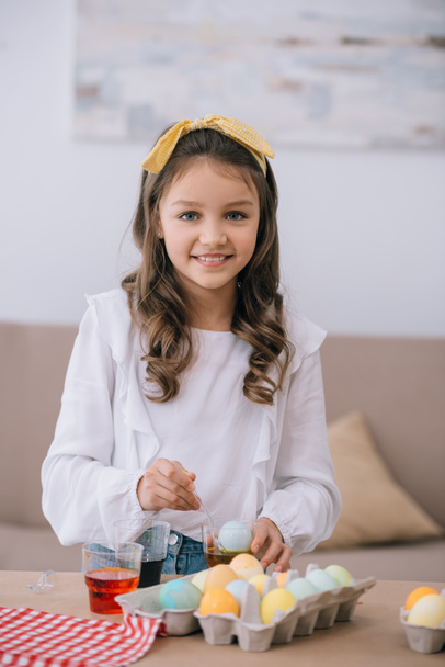 smiling little child painting easter eggs and looking at camera - Фото, зображення
