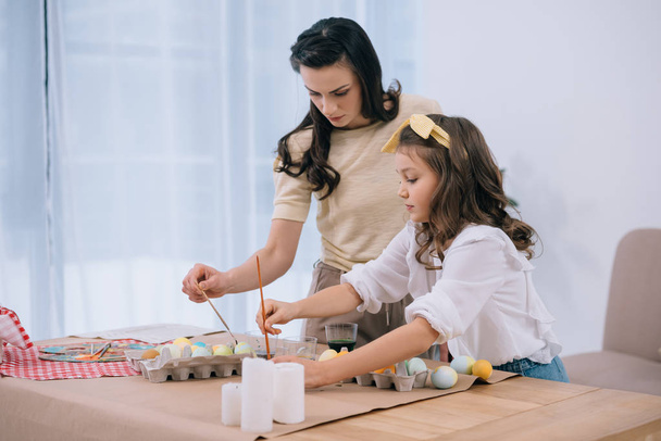 mother and adorable daughter painting easter eggs together - Photo, Image