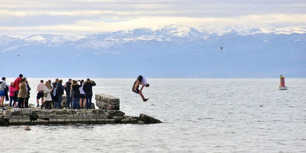 OHRID, MACEDONIA - JANUARY 19, 2017: Men jumping into freezing water during the celebration of Epiphany day in Ohrid, Macedonia - Фото, зображення