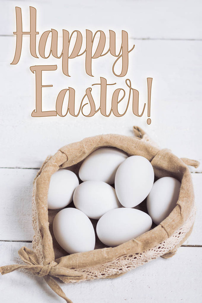 Easter concept. White chicken eggs in rustic sack on wooden background with text. - Foto, Imagem