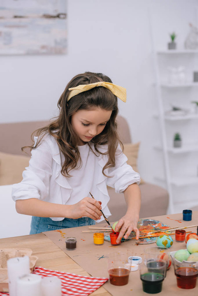 концентрированная маленькая девочка рисует пасхальные яйца
 - Фото, изображение