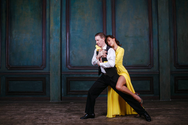 Mooie jongedame in gele jurk en man dance tango - Foto, afbeelding