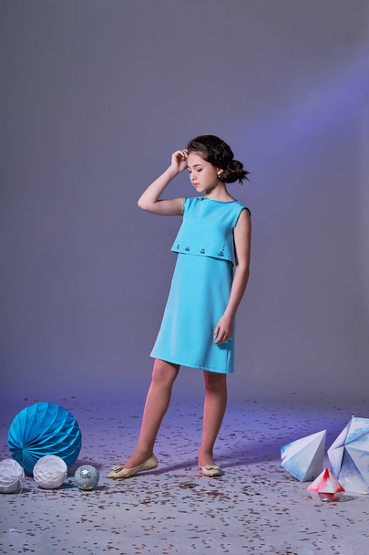 Pretty girl in an elegant blue dress for teenage girls with a make-up. Origami and minimalism. Fashion children. - 写真・画像