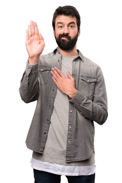 Hombre guapo con barba haciendo un juramento sobre fondo blanco
 - Foto, imagen