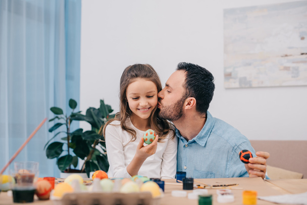 father kissing daughter while painting easter eggs - Foto, Imagem