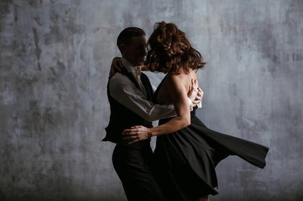 Молода красива жінка в чорній сукні і чоловік танцює танго
 - Фото, зображення