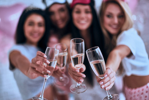 Four women in pajamas holding champagne glasses close to camera - Zdjęcie, obraz