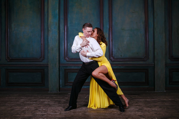 Young pretty woman in yellow dress and man dance tango - Photo, Image