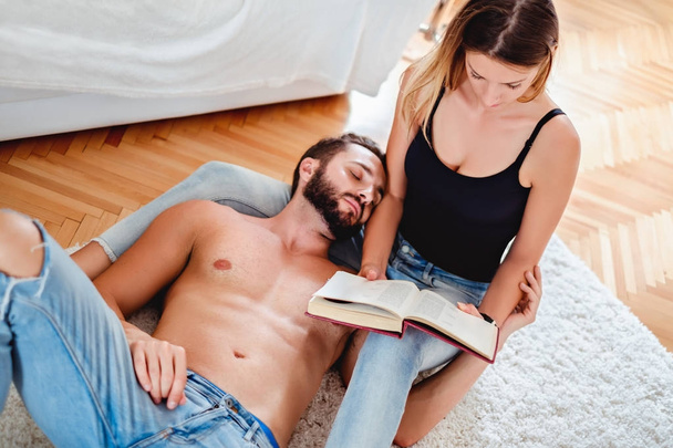 Girlfriend reading a book with boyfriend sleeping in her lap - Foto, afbeelding