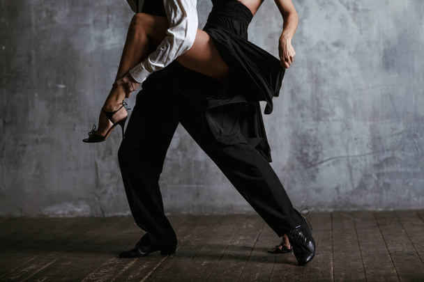 Jonge mooie vrouw in zwarte jurk en man dance tango - Foto, afbeelding