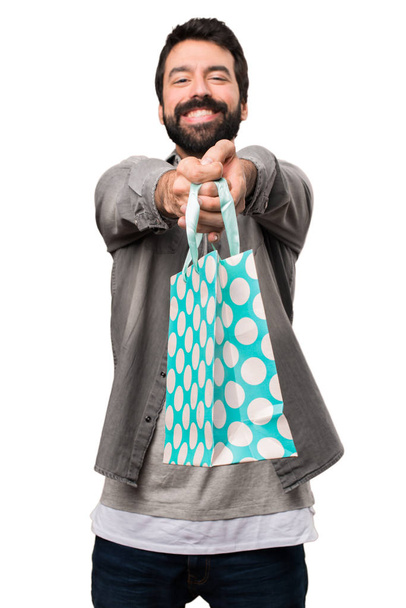 Όμορφος άνδρας με γενειάδα με τσάντα για ψώνια σε λευκό φόντο - Φωτογραφία, εικόνα
