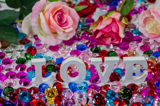 La palabra amor se encuentra en el área de diamantes de colores y rosas, la palabra amor es amor para el Día de San Valentín
. - Foto, imagen