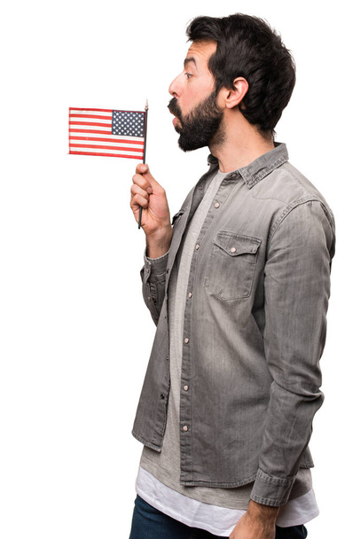 Hombre guapo con barba sosteniendo una bandera americana sobre fondo blanco
 - Foto, imagen