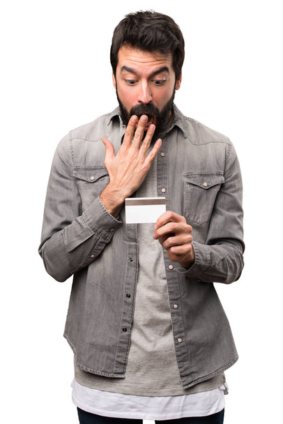 Sorprendido Hombre guapo con barba sosteniendo una tarjeta de crédito en blanco
 - Foto, imagen