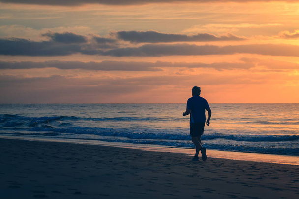 Man is running by the beach at sunrise. - Fotoğraf, Görsel