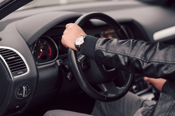 Businessman driving luxury modern car in the city. Close up man's hand with expensive watch on the wheel of the car. - Фото, изображение