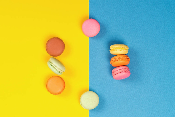 Colorful macaroons on a blue and yellow background. Minimal concept. Flat layout. - Фото, изображение