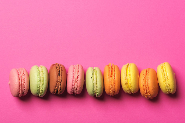 Colorful macarons on the pink bright paper background, top view, copyspace. - Foto, Bild