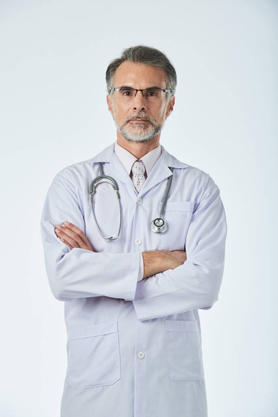 Portrait of confident doctor standing with his arms folded - 写真・画像
