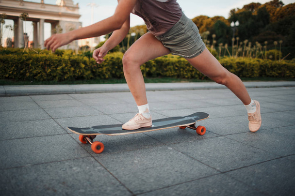 Young sporty woman riding on the longboard in the park - Foto, Imagen