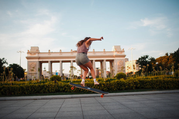 Jonge sportieve vrouw rijden op de longboard in het park - Foto, afbeelding
