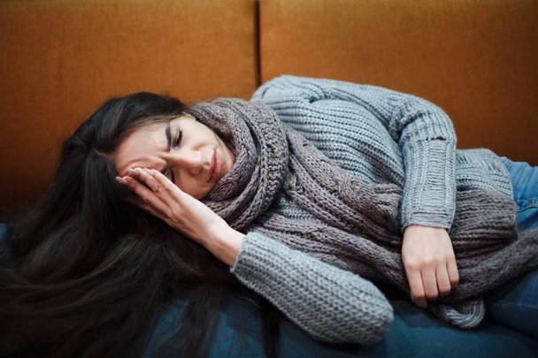 インフルエンザの風邪やアレルギーの症状。スカーフとベッドの上に敷設する一般的な風邪、アレルギー、組織にくしゃみ発熱を伴う病気の若い女性. - 写真・画像