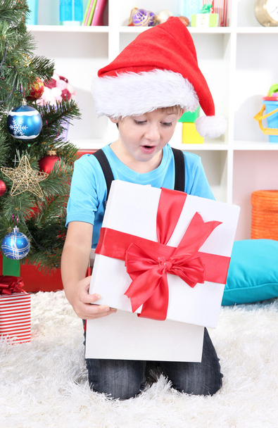 Little boy open his gifts near Christmas tree - Fotoğraf, Görsel