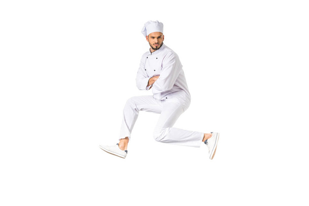 handsome young male chef jumping and looking at camera isolated on white - Fotografie, Obrázek
