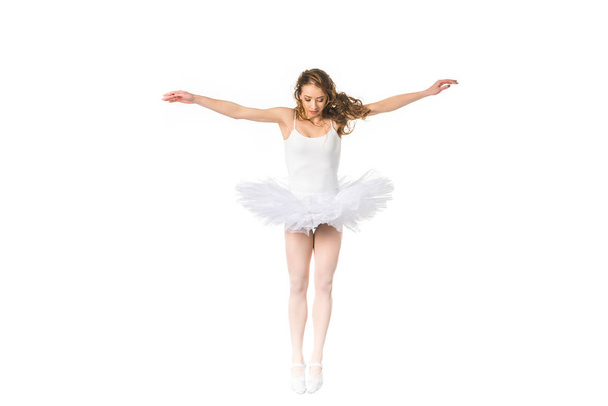 young ballerina with open arms jumping and looking down isolated on white - Fotó, kép