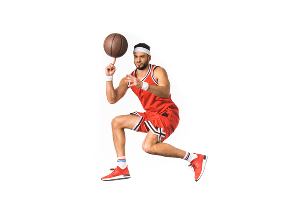 jonge basketbal speler draaiende bal op vinger geïsoleerd op wit - Foto, afbeelding