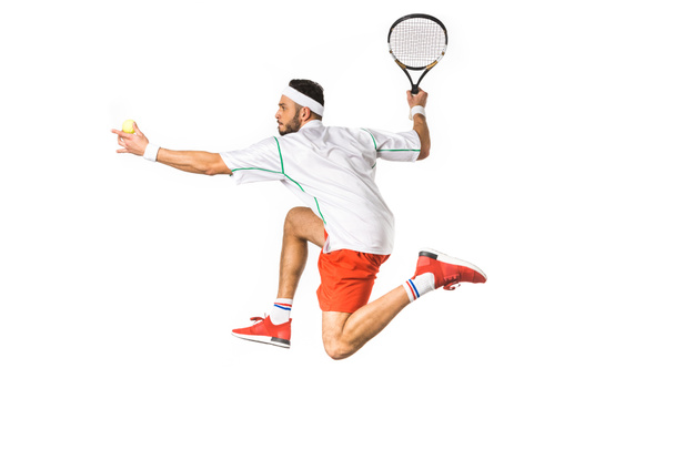 Seitenansicht eines jungen Sportlers mit Ball und Schläger beim Tennisspielen isoliert auf weiß - Foto, Bild