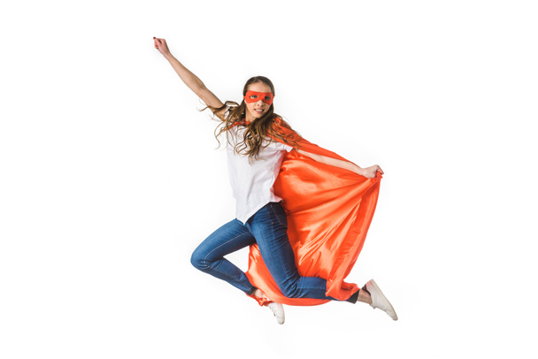 lachende jonge vrouw in rode mantel en masker vliegen geïsoleerd op wit - Foto, afbeelding