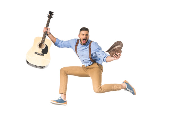 excited young musician with guitar and hat screaming at camera isolated on white - Foto, Bild