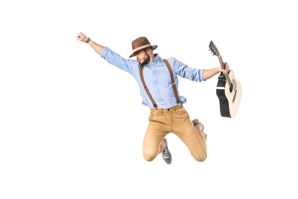young musician in hat holding guitar and flying with raised hand isolated on white - Foto, Bild
